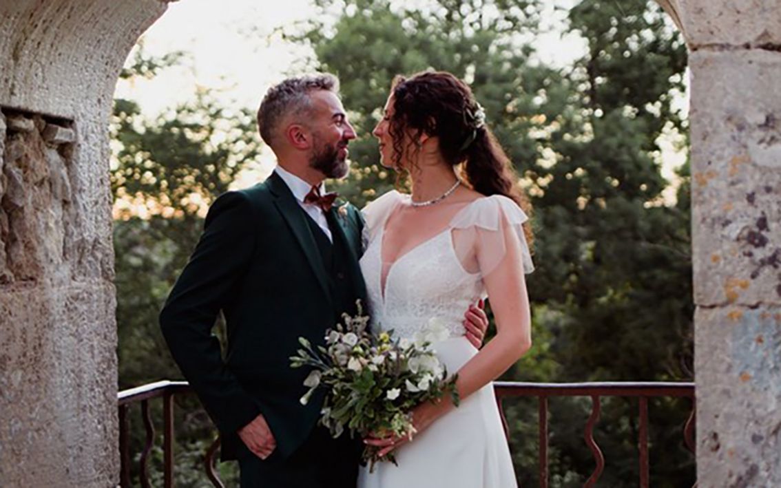 Un couple marié sous une arche en pierre avec un bouquet