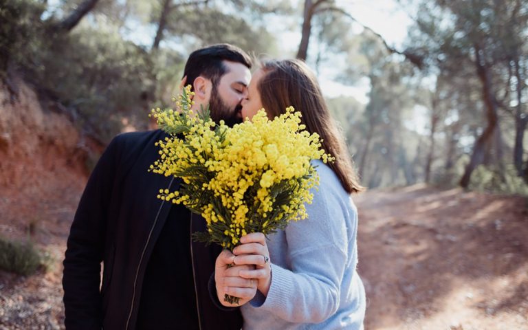 Photo d'un couple qui s'embrassent en tenant un bouquet de fleurs