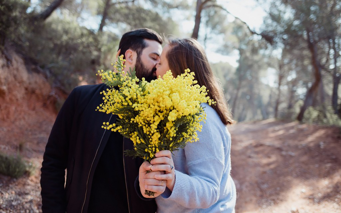 Photo d'un couple qui s'embrassent en tenant un bouquet de fleurs