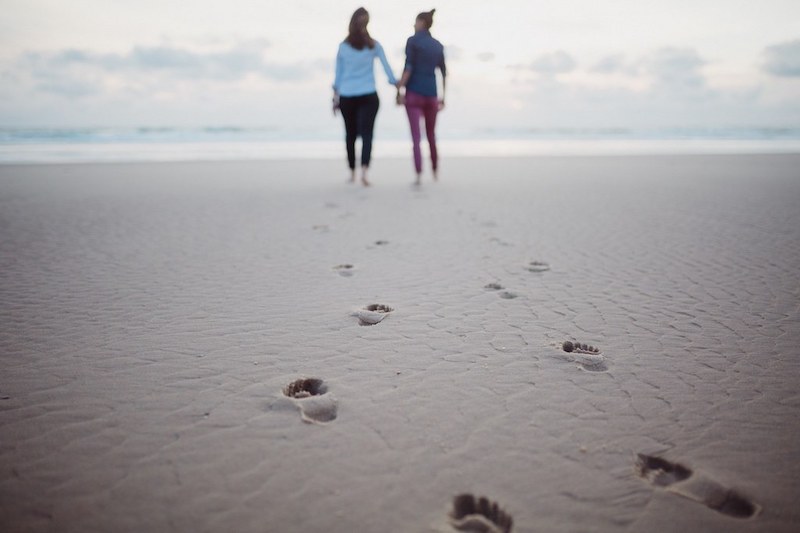 Un couple de femme se tient la main sur la plage